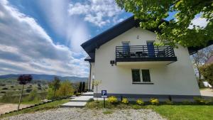 a white house with a balcony and mountains in the background at Noclegi Na Gołębiówce in Wadowice