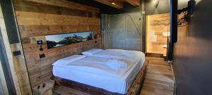 a bedroom with a large bed in a wooden wall at DolomitiBel Siberiana 2 SILVER in Braz
