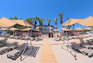 a sandy beach with lounge chairs and umbrellas at CLUB MONTE CARLO HoTEL in Alanya