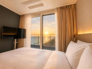 a hotel room with a bed and a large window at Emerson Suites Naksan in Yangyang