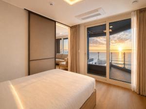 a bedroom with a bed and a view of the ocean at Emerson Suites Naksan in Yangyang