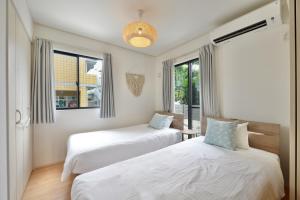 two beds in a room with two windows at 北谷町港2 in Chatan