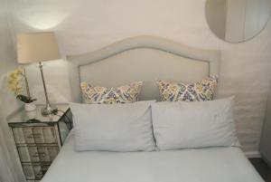 a bed with white pillows and a white headboard at Chalet Kudu in Ladismith +5 photos