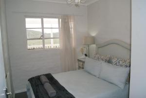 a white bedroom with a bed and a window at Chalet Kudu in Ladismith