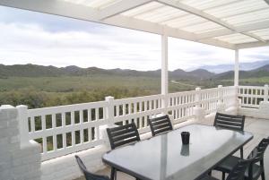 a white porch with a table and chairs and mountains at Chalet Kudu in Ladismith