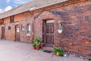 a brick building with a brown door and potted plants at Ponyhof Kudowa in Sonnewalde