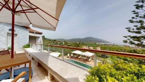 a balcony of a villa with a pool and an umbrella at Epidavros Villas - Gardenia Garden Retreat with Shared Pool in Nea Epidavros
