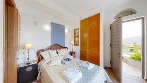 a bedroom with a bed and a large window at Epidavros Villas - Gardenia Garden Retreat with Shared Pool in Nea Epidavros
