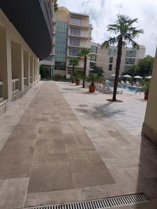 an empty sidewalk in a building with a palm tree at Sol e Mar in Sunny Beach