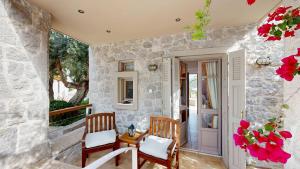 a stone walled porch with two chairs and a table at Epidavros Villas - Elia Garden Retreat with Shared Pool in Nea Epidavros
