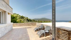 a patio with chairs and a table and a view of the ocean at Epidavros Villas, Thymari Garden & Seaview Retreat in Nea Epidavros