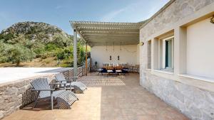 a patio with chairs and a table on a stone wall at Epidavros Villas, Thymari Garden & Seaview Retreat in Nea Epidavros