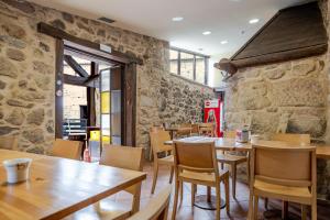 ein Restaurant mit Tischen und Stühlen und einer Steinmauer in der Unterkunft O Lagar de Jesus in Padrón