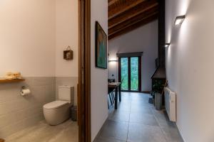 a bathroom with a toilet and a hallway with a table at Can Pont in Camprodon
