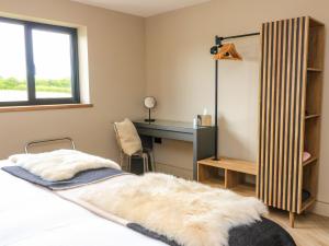 a bedroom with a desk and a bed with a furry blanket at The Cozie Sow in Yeovil