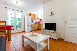 a living room with a white table and a tv at Gite les Mazets du Rouret in Saint-Christol-lès-Alès
