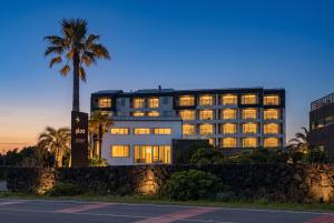 a building with lights on in front of a palm tree at Plott Archive Jeju in Jeju