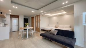 a bedroom with a bed and a table and a couch at Plott Archive Jeju in Jeju