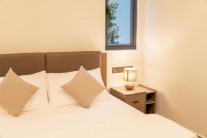 a bedroom with a bed with white pillows and a lamp at Pulsera Beach Residence Maldives by Circles Hospitality in Hulhumale