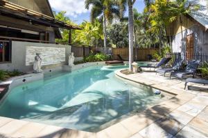 a swimming pool in a yard with two chairs and a house at Pure Magnetic Villa 9 in Nelly Bay