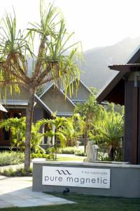 a sign in front of a building with a palm tree at Pure Magnetic Villa 8 in Nelly Bay