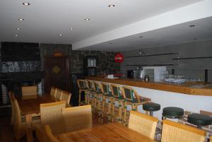 トレフェンにあるHotel Alpenrose Gerlitzenのバー、木製のテーブルと椅子が備わるレストランを提供しています。