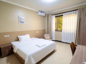 a bedroom with a white bed and a window at Cactus Hotel in Dar es Salaam
