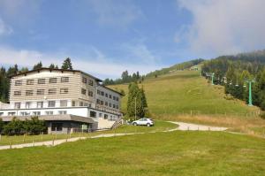 a building on a hill with a car on a road at Hotel Alpenrose Gerlitzen in Treffen