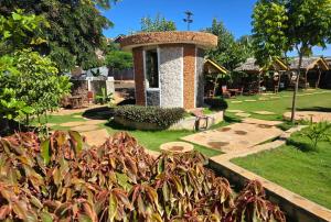 a garden with a stone tower in a park at Lesha Park Hotel in Libwezi