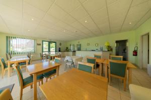 a restaurant with tables and chairs and a kitchen at Le Relais du Mess in Vacherauville
