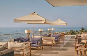 a deck with chairs and umbrellas on the beach at Mandarin Oriental, Muscat in Muscat