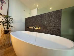 a white bath tub in a bathroom with a plant at Blue on Blue Apartment 1011 in Nelly Bay +14 photos