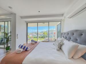 a bedroom with a large bed with a large window at Blue on Blue Apartment 1011 in Nelly Bay