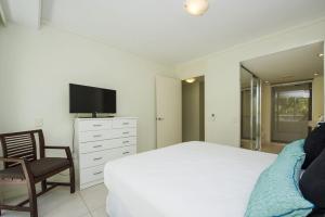 a bedroom with a bed and a tv and a chair at Blue on Blue Apartment 813 in Nelly Bay +8 photos