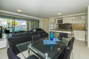 a living room with a glass table and black chairs at Blue on Blue Apartment 813 in Nelly Bay