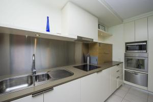 a kitchen with white cabinets and a sink at Blue on Blue Apartment 813 in Nelly Bay