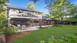 a barn style house with a patio and a yard at The Castle Wentworth Falls in Wentworth Falls