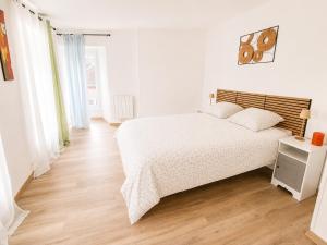 a white bedroom with a bed and a wooden floor at Maison 6 pers - Entre mer & Mont-Saint-Michel in Beauchamps