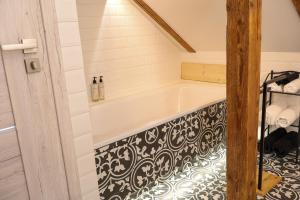 a bathroom with a tub with a black and white tile floor at Pliusas Residence in Jurbarkas +21 photos
