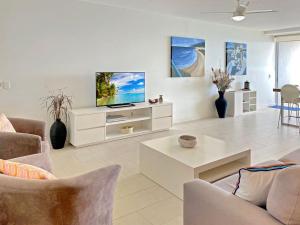 a living room with a tv on a white wall at 1 Bright Point Apartment 4203 in Nelly Bay