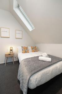 a white bedroom with a bed and a table at Sarahs Scenic Stay Mountain Lake Views in Queenstown