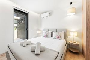 a white bedroom with a large bed and a window at GuestReady - Beachfront retreat with pools in Apúlia
