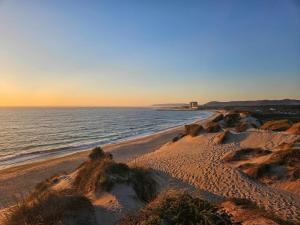 a beach with a building in the distance and the ocean at GuestReady - Beachfront retreat with pools in Apúlia