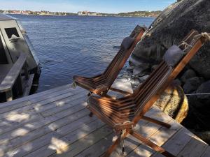 two wooden chairs sitting on a dock next to the water at Stockholm Archipelago Igloo Hut in Tynningö