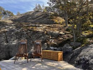 two chairs sitting on a deck next to a mountain at Stockholm Archipelago Igloo Hut in Tynningö