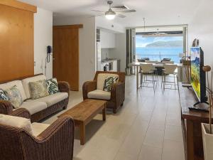 a living room with couches and a table and a kitchen at 1 Bright Point Apartment 2303 in Nelly Bay +12 photos