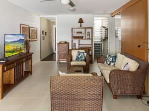 a living room with wicker chairs and a television at 1 Bright Point Apartment 2303 in Nelly Bay