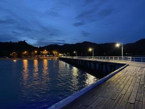 a wooden pier with lights on the water at night at 1 Bright Point Apartment 2303 in Nelly Bay