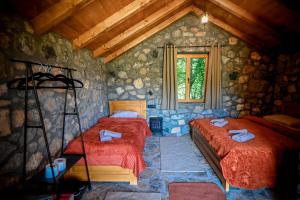 a bedroom with two beds in a stone wall at Cottages Serdar in Mojkovac