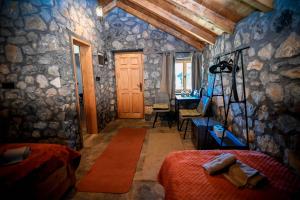a bedroom with two beds and a stone wall at Cottages Serdar in Mojkovac